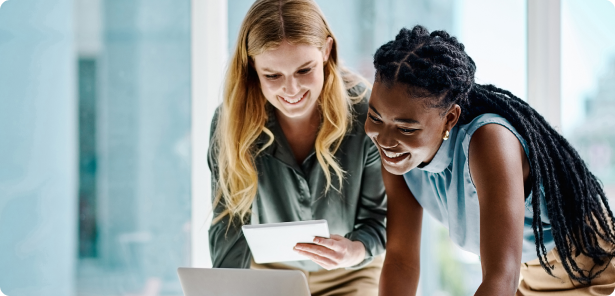 Two people smiling whiling looking at a laptop computer in a modern office